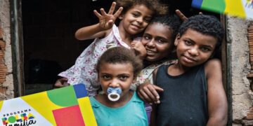 Família de beneficiários do Bolsa Família sorrindo e posando para foto, com cartão do programa visível, destacando os benefícios para enfrentar os desafios financeiros